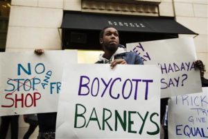 Demonstrators stand in front of a Barneys luxury department store of with signs decrying allegations that Barney's and Macy's stores have unfair security policies aimed at minorities in New York