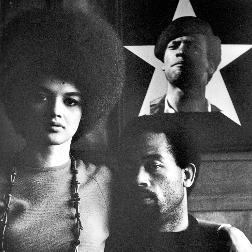 Eldridge-Cleaver-and-Wife-Kathleen-with-portrait-of-Huey-Newton-Algiers-1970.jpg