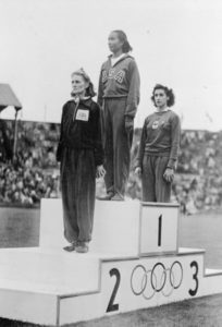 Alice Coachman, (center), of Albany, GA., stands on the winner's section of the Olympic podium at Wembley Stadium, Wembley, England, August 7, 1948, to receive the gold medal for winning the women's high jump.   Photo credit: Associated Press