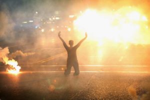 Tear gas rains down on a woman kneeling in the street with her hands in the air during a demonstration in Ferguson on Aug. 17, 2014. The "hands up, don't shoot" pose became the defining gesture of the protests. Scott Olson—Getty Images