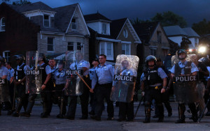 Police in riot gear stand guard as protesters gather Wednesday, Aug. 19, 2015, in St. Louis. A black 18-year-old fleeing from officers serving a search warrant at a home in a crime-troubled section of St. Louis was fatally shot Wednesday by police after he pointed a gun at them, the city's police chief said. (Laurie Skrivan/St. Louis Post-Dispatch via AP)