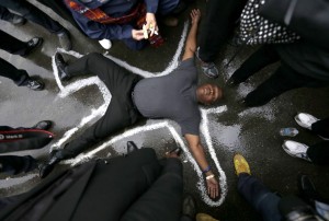 Pastor Charles Burton lies on the driveway of the Ferguson, Mo., police station in October, outlined in chalk as a memorial to Michael Brown, who was fatally shot by a white police officer. In New York City, another unarmed black man, Eric Garner, died after a white officer put him in a chokehold. Associated Press