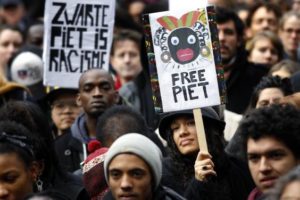 Demonstrators hold signs reading 'Black Pete is Rascism' and 'Free Black Pete' during a demonstration against Zwarte Piet (Black Pete) in Amsterdam