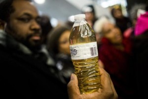 JAKE MAY/AP Pastor David Bullock holds up a bottle of Flint water, which has been deeply contaminated with lead. 