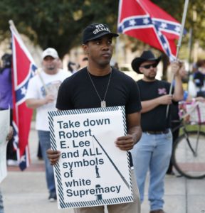 In this Dec. 10, 2015 file photo, an unidentified participant holds a sign during a rally lead by the Take 'em Down Coalition, as confederate heritage supporters bear confederate flags nearby in front of City Hall in New Orleans. GERALD HERBERT, AP