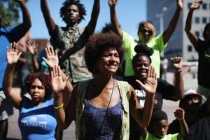 Demonstrators raise their hands and chant "hands up, don't shoot" during a protest over the killing of Michael Brown on Aug. 12 in Clayton, Mo. Some reports state that Brown hand his hands in the air when he was shot and killed by a police officer on Saturday in suburban Ferguson, Mo. Two days of unrest including rioting and looting have followed the shooting in Ferguson. Browns parents have publicly asked for order. (Scott Olson/Getty Images)