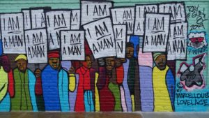 The "I'm a Man" mural is designed by rap artist Marcellous Lovelace in a modern graffiti style and installed by BLK75. It can be found on S Man St in Memphis, TN, USA, close to the National Civil Rights Museum. It shows the Sanitation Workers Protest March on March 28, 1968, an important event of the Civil Rights Movement, originally captured by photographer Richard L. Copley.