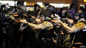 Police officers point their weapons at demonstrators protesting against the shooting death of Michael Brown in Ferguson, MO. Image courtesy of Reuters.