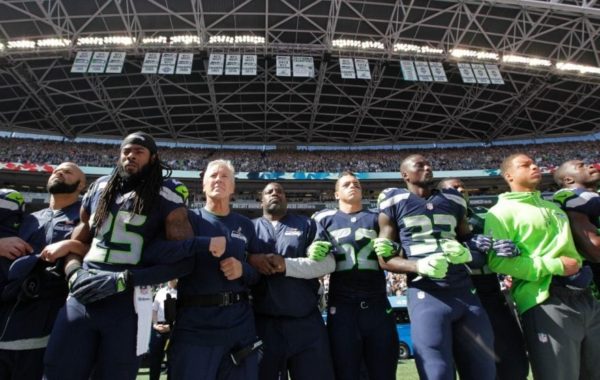 Seattle Seahawks players and coaches stand and link arms during the playing of the National Anthem. (AP).