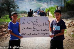 Palestinian kids at a hold up a sign in solidarity with Eric Garner and US demonstrators for racial justice. Photo by Hamdi Abu Rahma.