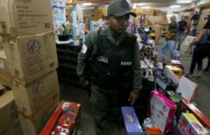 A handout photo released by Venezuelan News Agency (AVN) shows a member of Venezuelan Armed Forces walking among boxes of toys during an operation at a toy store in Caracas, Venezuela, on Friday