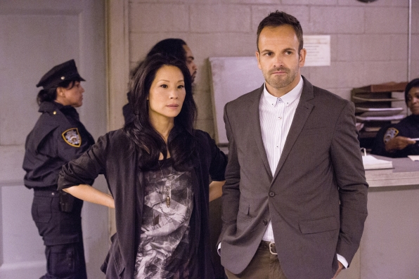 Holmes (Jonny Lee Miller, right) and Watson (Lucy Liu, left) work to find a masked gunman before he strikes again.