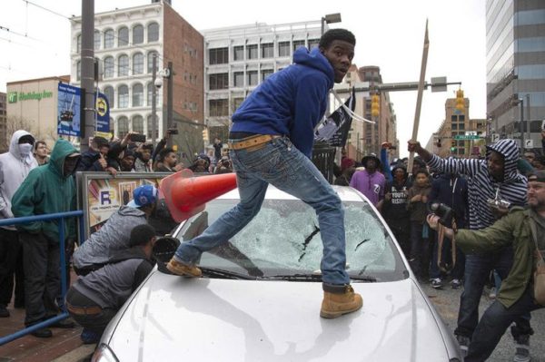Demonstrators destroy the windshield of a Baltimore Police car as they protest the death Freddie Gray, an African American man who died of spinal cord injuries in police custody, in Baltimore, Maryland, April 25, 2015. Protesters returned to Baltimore's streets Saturday to vent outrage over the death of Gray on April 12.      AFP PHOTO/JIM WATSON        (Photo credit should read JIM WATSON/AFP/Getty Images)