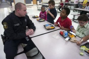 Photo: Kelli Cardinal Lima Police officer Nate Garlock talks with students during their lunch period at Freedom Elementary School in Lima.