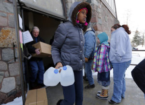 Genetha Campbell carries free water being distributed at the Lincoln Park United Methodist Church in Flint. (Paul Sancya / AP)