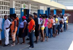 Voters wait in line outside a poling station during the Jamaican General Elections in Kingston