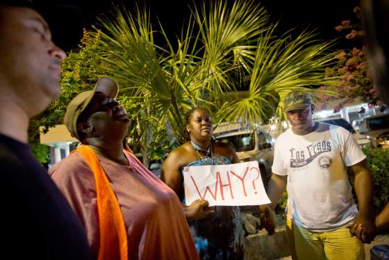 Surreace Cox, of North Charleston, S.C., holds a sign during a prayer vigil down the street from the Emanuel AME Church early Thursday, June 18, 2015, following a shooting Wednesday night in Charleston, S.C. (AP Photo/David Goldman)