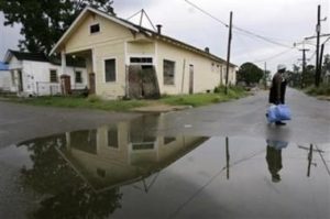 Woman walks alongside puddle in New Orleans 9th ward. 
