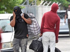 One of the 42 people who were deported from the United Kingdom on Wednesday covers his face to shield his identity as he leaves the police Mobile Reserve facility in the Vineyard Town area of Kingston. (Photo: Michael Gordon)