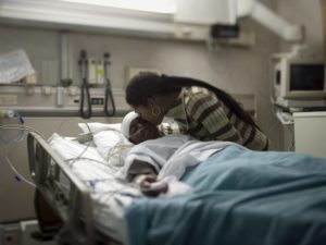 Close-up of a mother kissing her son in the hospital