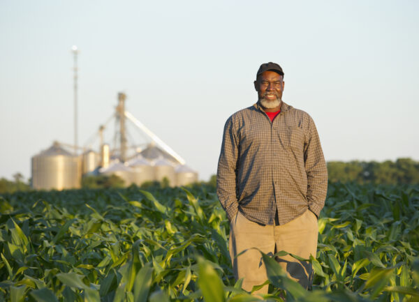 Black farmer standing in crop field