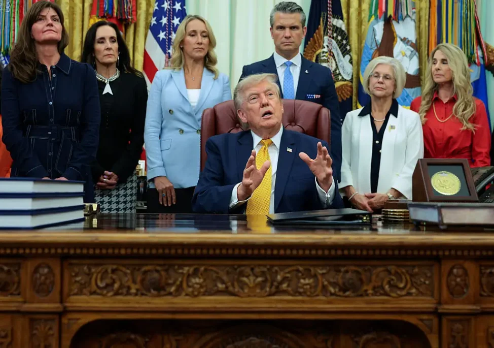U.S. President Donald Trump answers reporters' questions after signing an executive order establishing the President's Military Spouse Commission with Desiree Thompson Sayle (L), Secretary of War Pete Hegseth (3r R) and his wife Jennifer Hegseth (3rd L) in the Oval Office at the White House on August 03, 2026 in Washington, DC. The commission will advise the president about issues affecting military families and provide recommendations to improve quality of life and military readiness. (Photo by Chip Somodevilla/Getty Images)